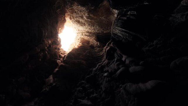 Rotating shot inside Ibiza cave looking up at sunlight entering through rocky opening.