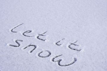 Written LET IT SNOW on snow background message ice outdoor on ground in winter. Writing text sign and drawing on field in frozen background. Weather is changing cold season has arrived. Mockup Copy