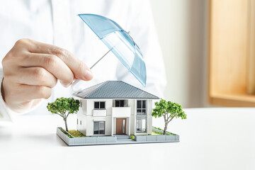 傘で安全に守られる家の模型　住宅の火災保険や地震保険　家のセキュリティ