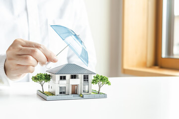傘で安全に守られる家の模型　住宅の火災保険や地震保険　家のセキュリティ