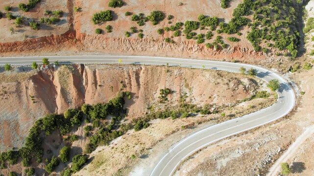 Aerial view of serpentine narrow road snaking between mountains in West Greece. A road full of twists and turns winding sharply up the mountain in Peloponnese region, Greece.