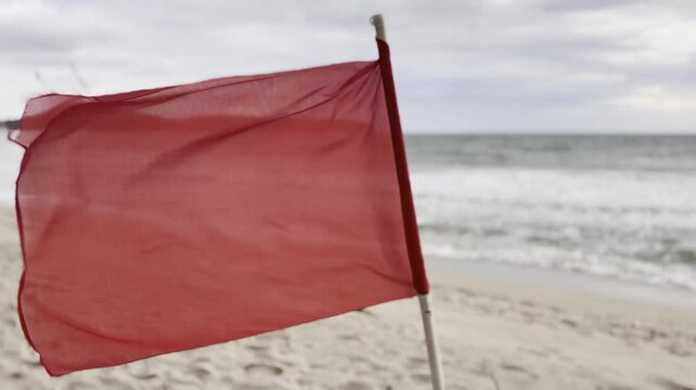 Red warning flag on stormy ocean beach