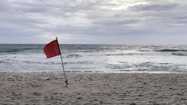 Red warning flag on stormy ocean beach
