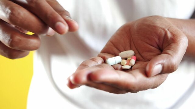 Person holding various medicine pills in open hand for health care and pharmaceutical concept