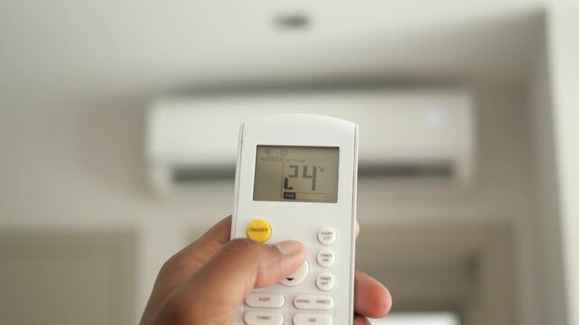 Person's hand adjusting air conditioner temperature using remote control motion