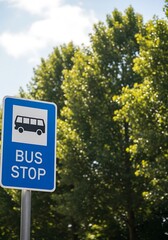 Rectangular blue traffic sign indicating a public transportation waiting area stands against a backdrop of lush green foliage and bright sky.