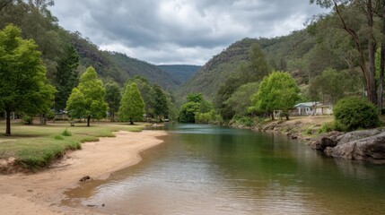 Obraz premium Serene River Landscape with Lush Green Trees and Mountains Under a Cloudy Sky in Australia’s Rural Countryside