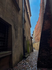 Narrow alleyway with old buildings and cloudy sky in city