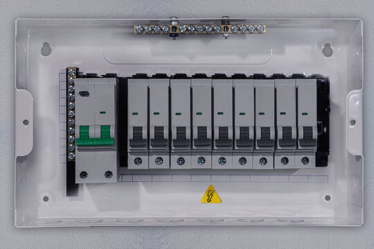 Close-up front view of a residential electrical distribution board mounted on a wall, featuring multiple miniature circuit breakers (MCB) and main breaker switch. Clean and organized electrical panel 