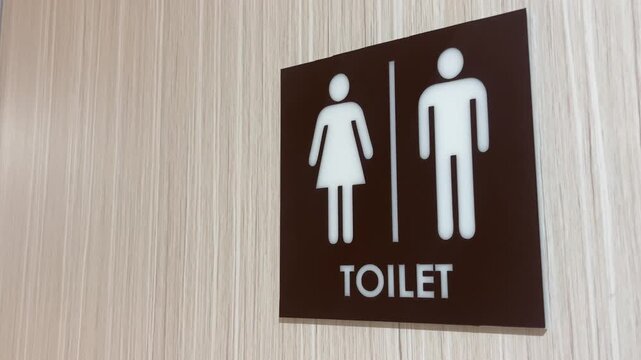 Close up of unisex restroom sign on wooden wall or door. brown, black, white. Public toilet sign showing facilities for male or female. icon. copy space, empty, free, negative, text, design.