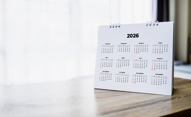 White desk calendar for year 2026 on wooden table with copy space. Ideal for planning, scheduling, business organization and time management concepts.