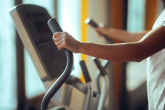 Hands Holding the Handles of an Elliptical Machine 
Person firmly grasping an elliptical moving handlebars
