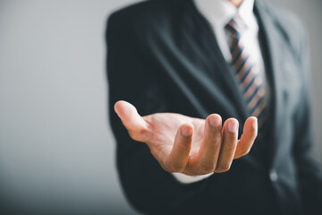 Fototapeta premium Closeup of a businessman's open hand, fingers extended, against a blurred background of his suit and tie.
