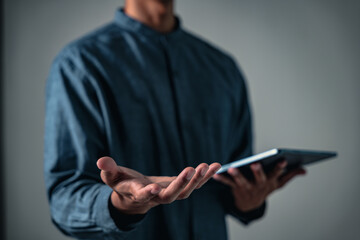 Pose of a modern man making a hand gesture or sign while posing with a digital tablet, he uses this...