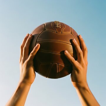 Hands lovingly hold a vintage leather football against a clear sky. 2026 soccer world championship.
