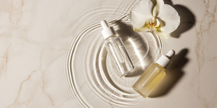 Luxury Skincare Serum Bottles with White Orchid and Water Ripples on Marble Background