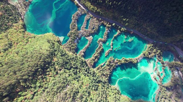 Drone view of Jiuzhaigou National Park in autumn in Sichuan Province China. It features cascading waterfalls, turquoise blue lakes, and stunning mountain valleys. 4K real time footage travel concept