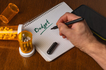 Writing a budget plan with medication and phone nearby