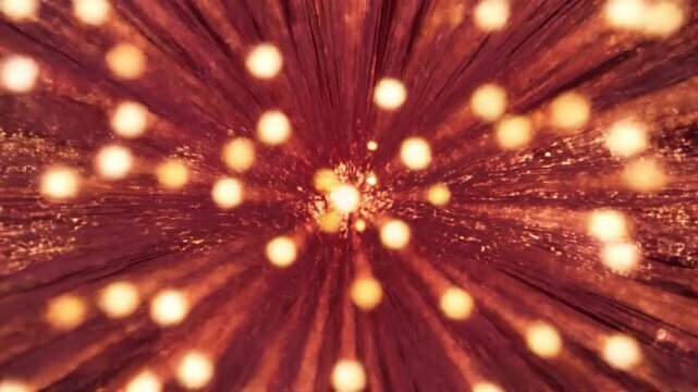 Vibrant golden particles explode and radiate against a deep red background