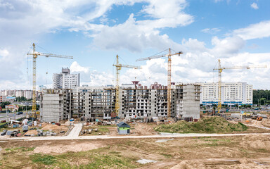 city residential area under construction. building site with cranes on blue cloudy sky background. aerial drone photo.