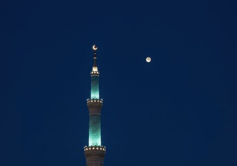 Obraz premium Stunning illuminated minaret tower against a dark blue evening sky, adorned with crescent moon lights, marking a peaceful religious holiday celebration, moon, tall, structure