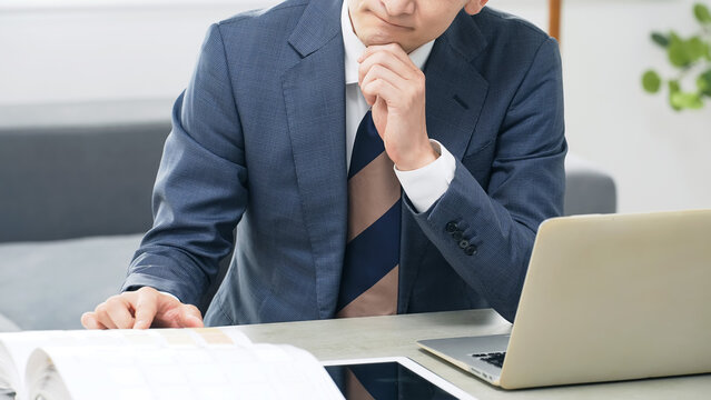 オフィスで仕事をしながら悩む男性ビジネスパーソン