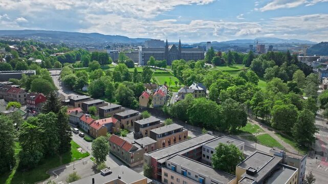 Aerial drone view of central Trondheim, Norway. Norwegian streets, riverfront greenery, and distant church spires fill the city panorama.