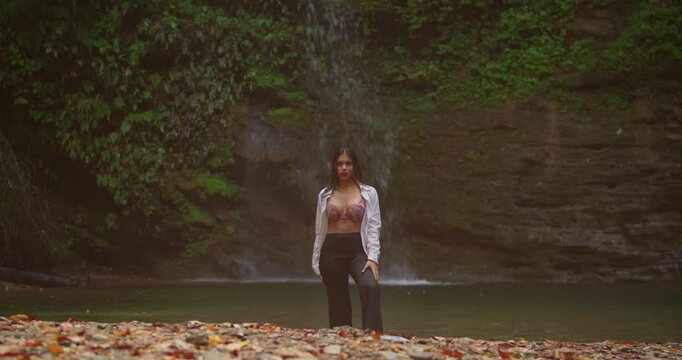 Cinematic shot of a woman wading into a crystal-clear jungle pool, a massive waterfall behind her, 8k resolution, highly detailed skin textures.