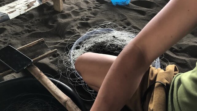 fisherman is attaching multiple hooks to a nylon fishing line.