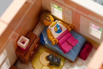 Fototapeta premium Tambov, Russian Federation - February 11, 2026 Lego woman minifigure lying on a bed in a miniature bedroom with cat.