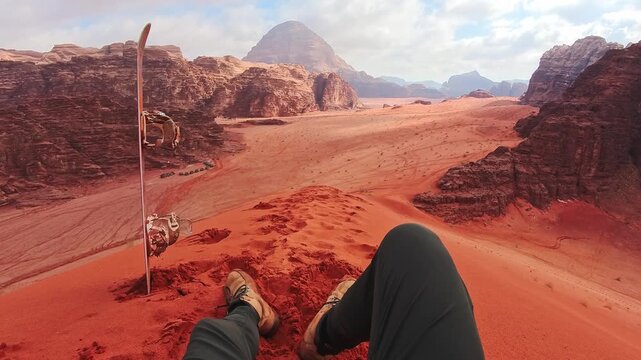 Sandboarding view from red dune Wadi Rum Jordan, traveler POV with board, desert adventure freedom concept. Wadi rum tours and Sand boarding, hiking, wandering outdoors activities
