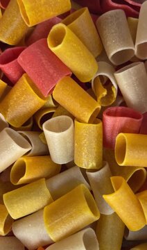 Close up of colorful dry tubular pasta or snack pellets in red yellow and white colors