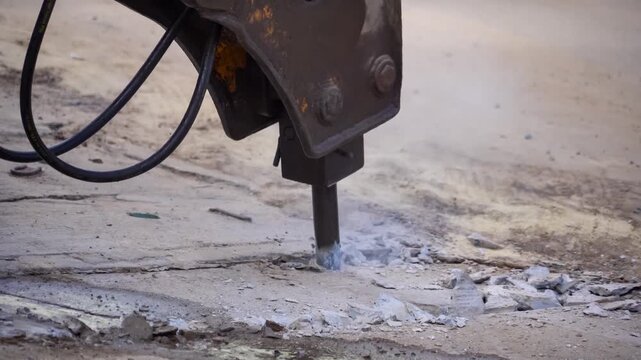 Concrete Demolition: A close-up shot of a powerful jackhammer breaking concrete, capturing the raw force and the destructive process of demolition in a construction zone.