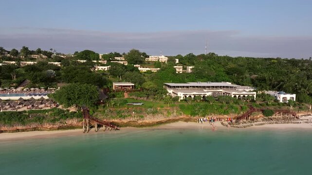 Aerial view of paradise beach with white sand and turquoise ocean.Tourists walk along resorts and restaurants on the shore. Nungwi and Kendwa beach, Zanzibar, Tanzania.
