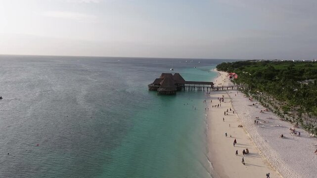Top view of traditional wooden bungalow with thatched roof and pier bridge on stilts.Kendwa beach with sand and ocean. Nungwi and Kendwa beach coastline, Zanzibar, Tanzania.