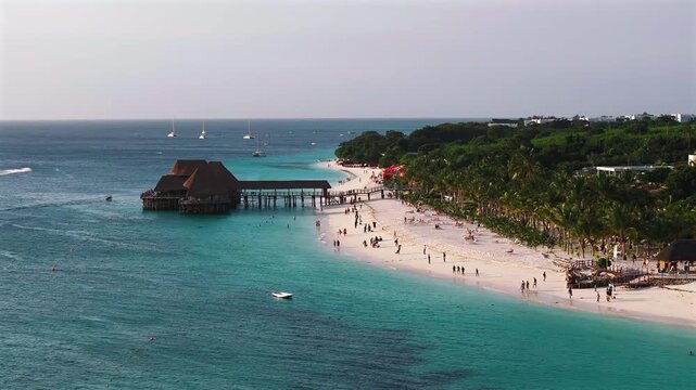 Panning view of traditional wooden bungalow with thatched roof and pier bridge on stilts.Kendwa beach with sand and ocean. Nungwi and Kendwa beach coastline, Zanzibar, Tanzania.