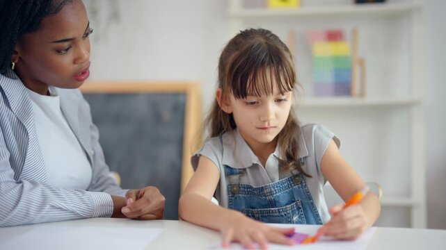 African woman tutor guide young child through learning activities on table.