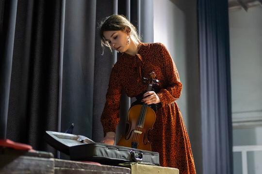 female violinist takes out her violin while standing backstage