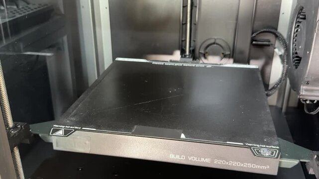3D printer build plate rises along the vertical axis during setup, showing precise mechanical movement and calibration.