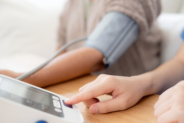 Fototapeta premium Asian woman nurse measuring blood pressure senior patient, medical checking for hypertension monitoring, caregiver support elderly woman with arterial blood pressure device, routine health checkup.