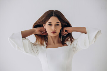 Naklejka premium Beauty portrait of a model, a beautiful brunette girl with straight long hair in a white dress, healthy and natural on a white background