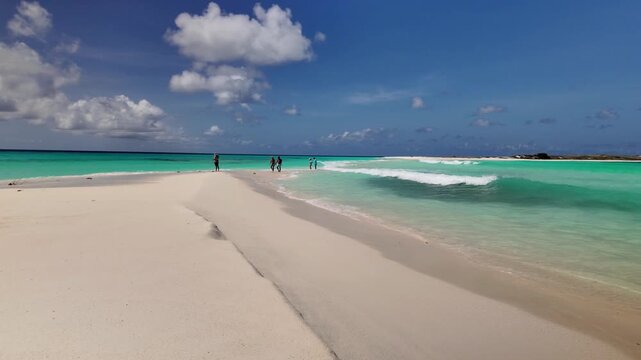 Breathtaking panoramic view of iconic natural sand bridge in Los Roques, Venezuela, showing people walking between two turquoise ocean shores.