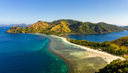 Obraz premium Experience paradise with this stunning aerial shot of a white sand beach, crystal clear turquoise waters, and lush green mountains. Perfect for travel and nature inspiration.