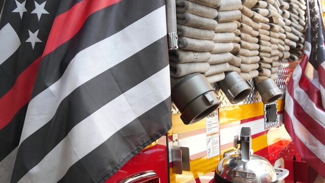 Red thin line black american flag on firefighter truck. Hose of firetruck and fire fighters symbol in New York, United States. 911 remembrance, fire department engine vehicle. September 11 Patriot Day