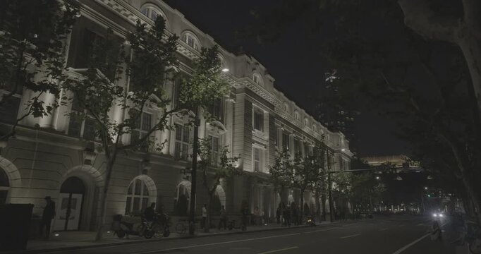 Lined Trees and Warmly Lit Building Creating Serene Night Atmosphere