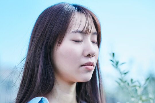 屋外で目を閉じる若い女性