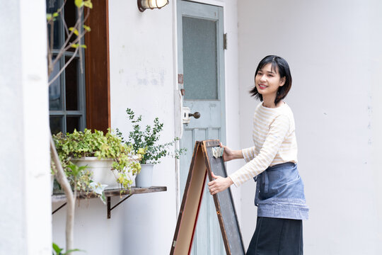 お店の前で看板を出している女性