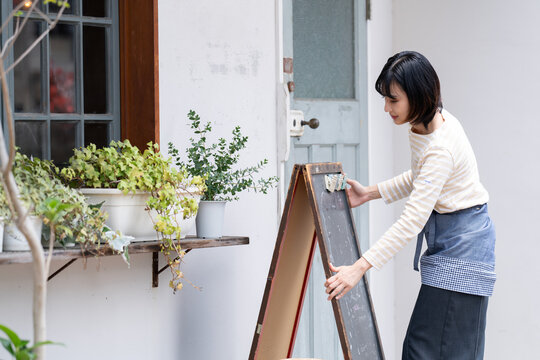お店の前で看板を出している女性
