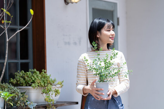 お店の前で鉢植えを持っている女性