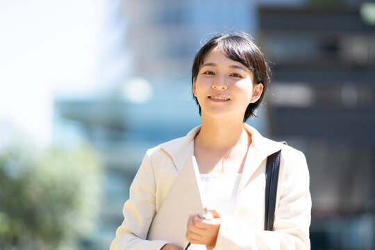 パソコンを抱えて外を歩いている女性
